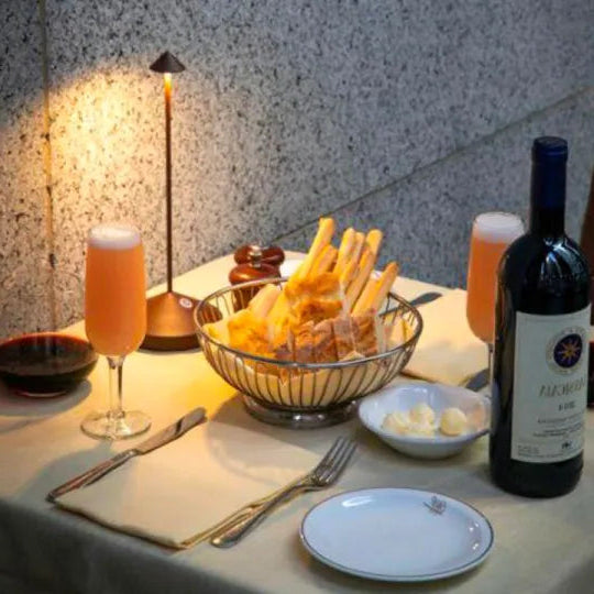 Dinner table setting with wine, appetizers, and drinks on a textured wall background