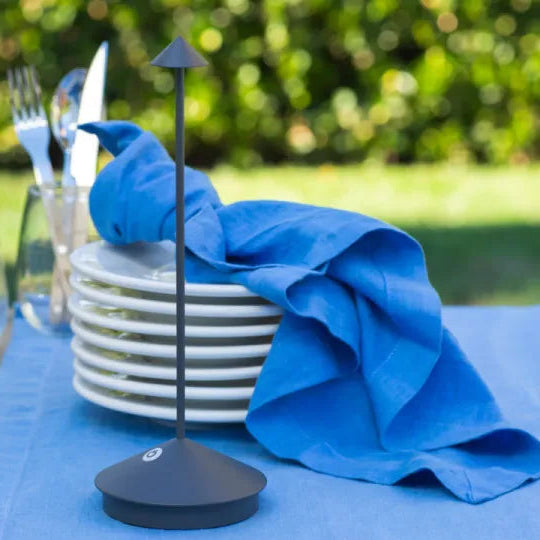 Black napkin holder with blue napkin on a table lamp outdoors