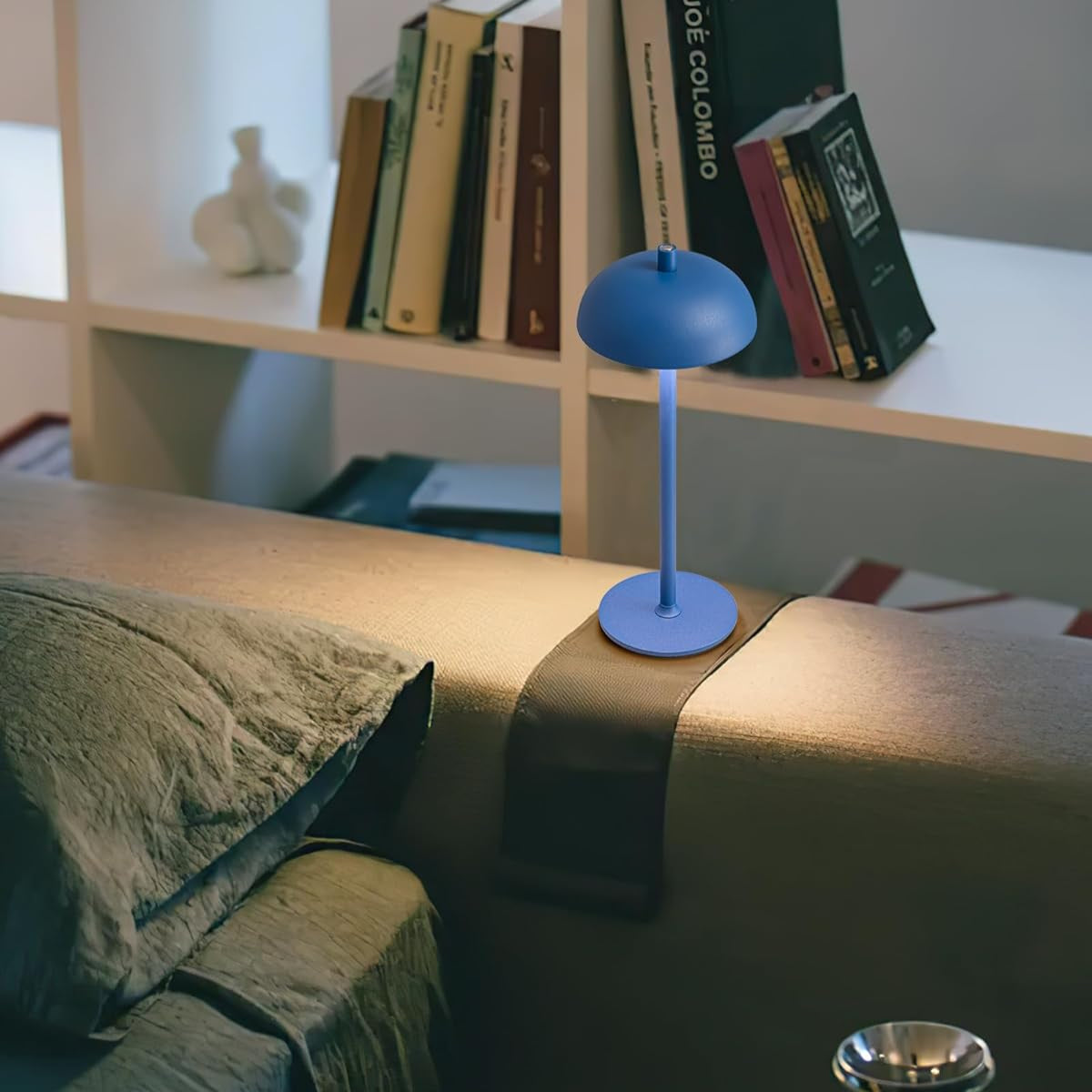 Blue table lamp on a sofa with books in the background