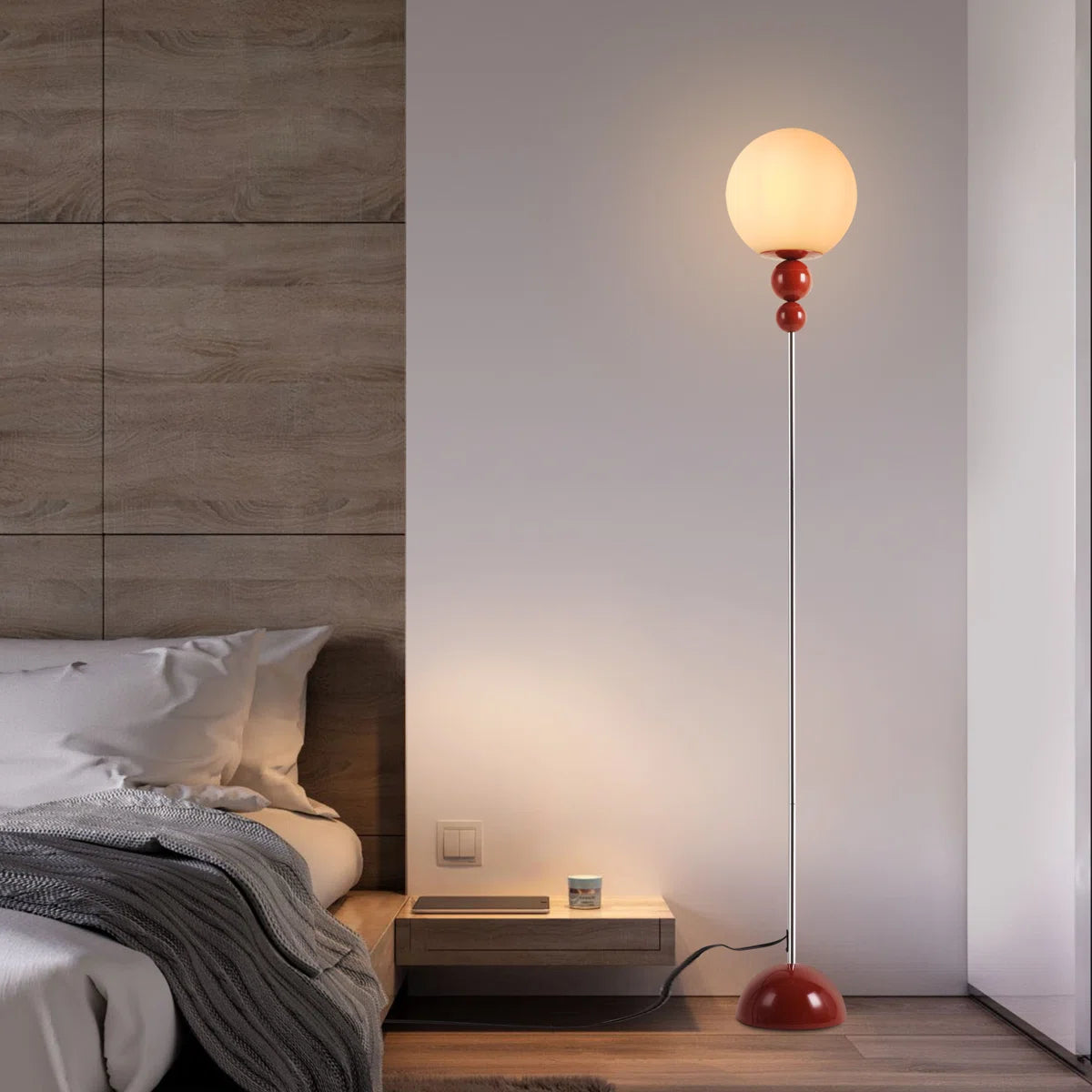 Modern floor lamp with a red base in a bedroom setting.