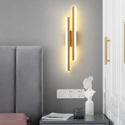 Modern wall sconce on a gray wall above a nightstand with decorative items.