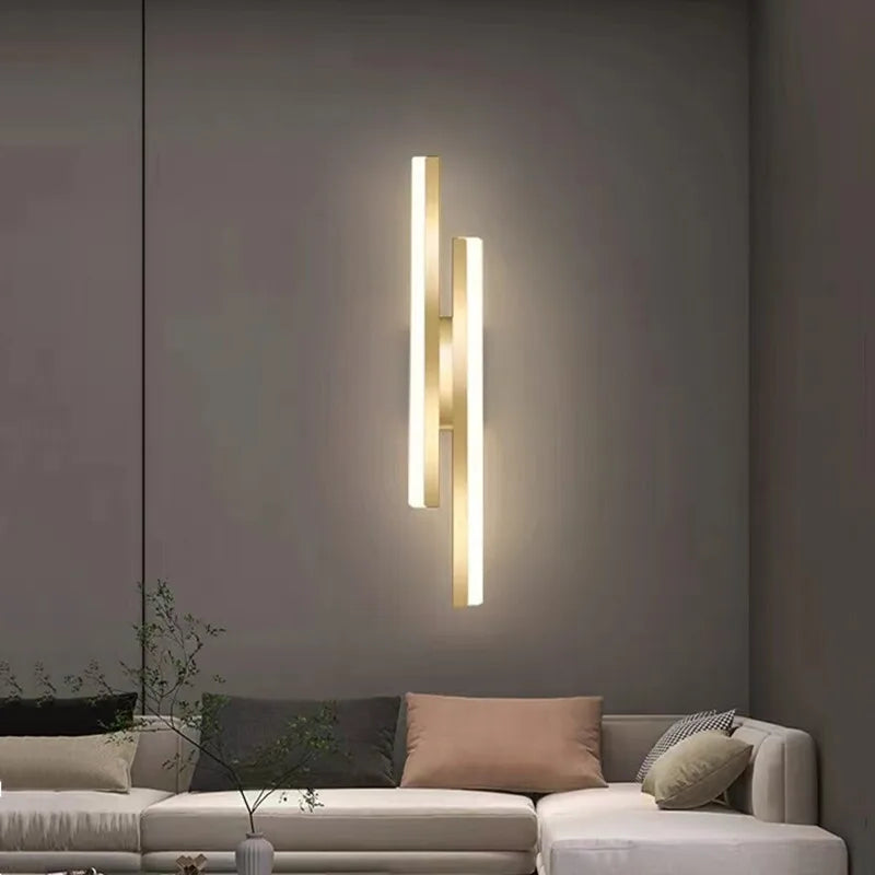 Modern wall sconce lighting fixture on a gray wall above a sofa.