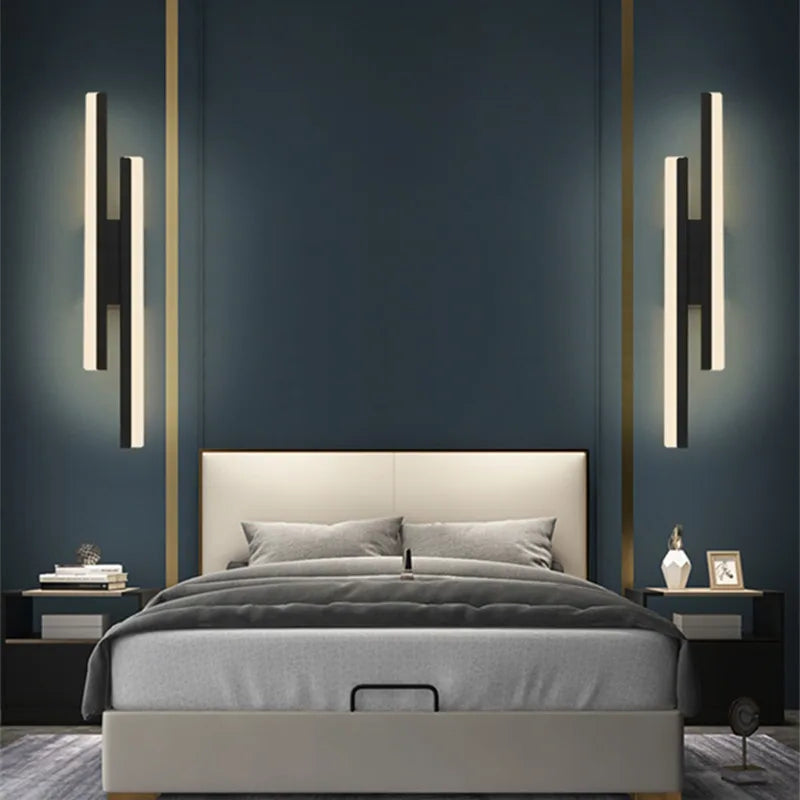 Modern bedroom with a bed, nightstands, and wall lights against a dark blue wall.