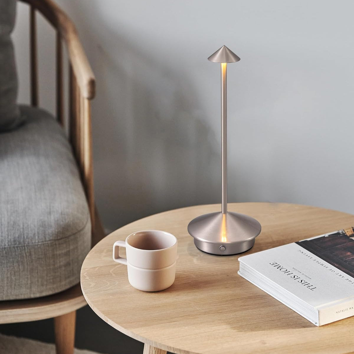 Modern table lamp on a wooden table with a cup and book in a cozy room.