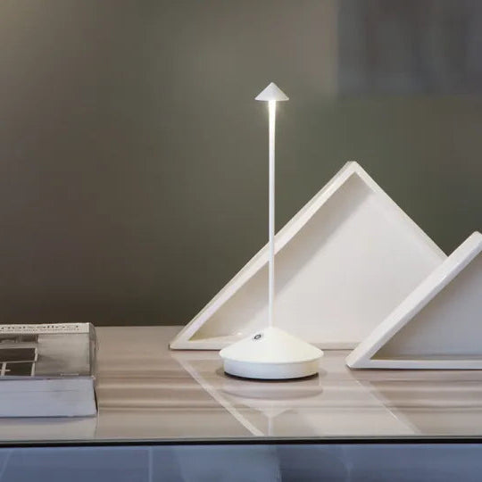 Modern white lamp on a wooden surface with a minimalistic design.