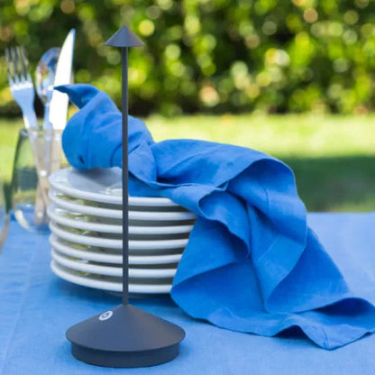 Black napkin holder with blue napkin on a table lamp outdoors