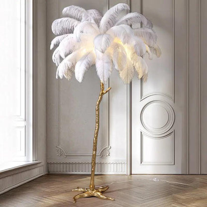 Decorative floor lamp with white feathers and gold base in a room with wooden flooring and white walls.