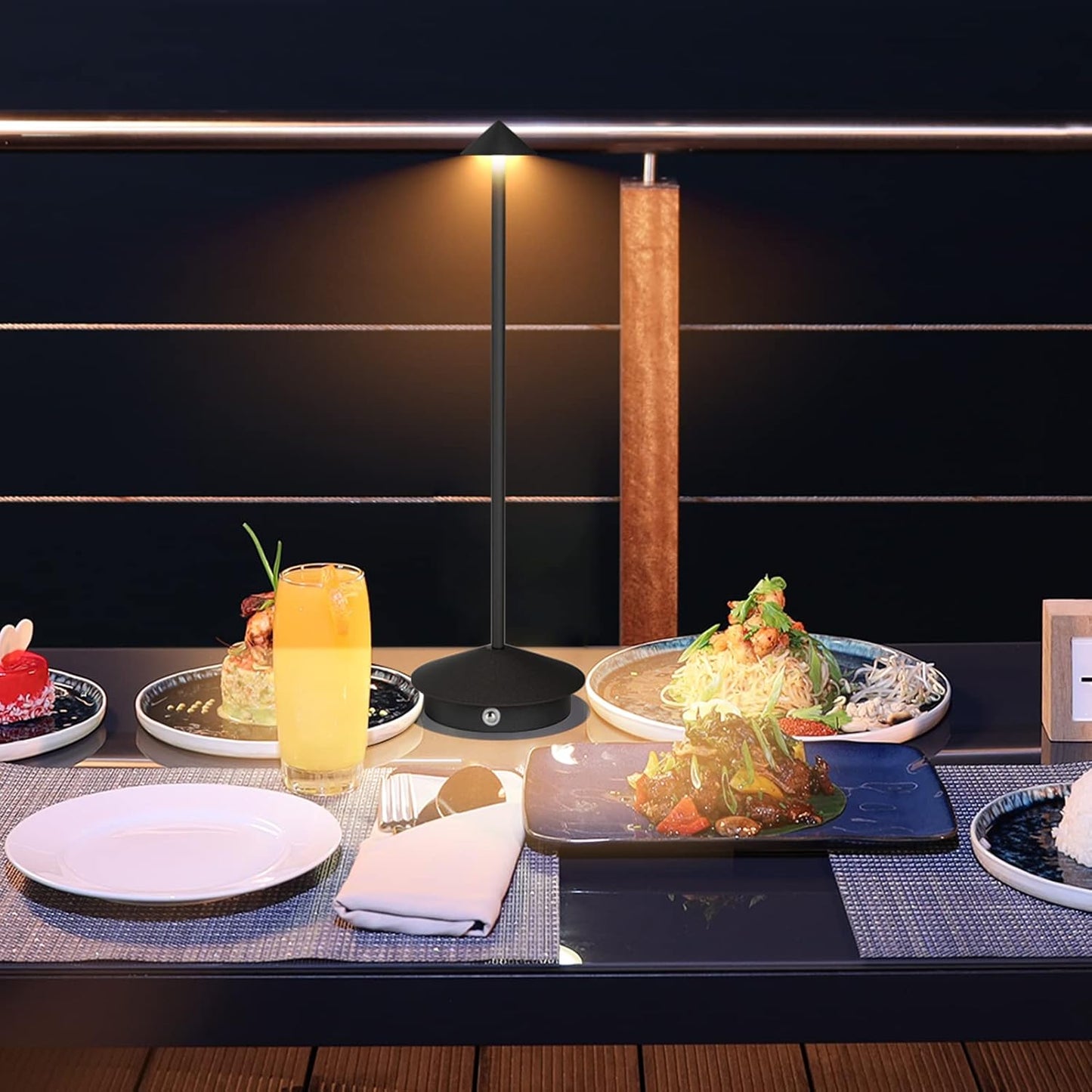 Dessert table setting with various dishes and a glass of orange juice on a dark background.